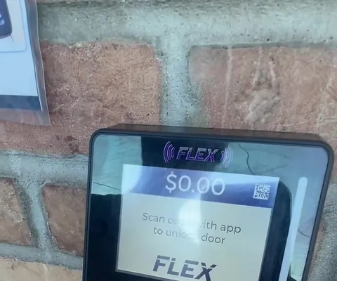 The FasCard reader on the brick wall beside the front door - scan its QR code with the FasCard app to unlock the door